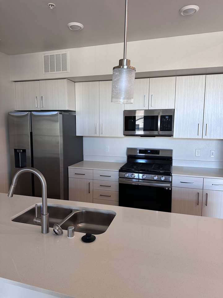 Modern Reno apartment kitchen with an island sink, cabinetry, refrigerator, and gas range on the opposite wall