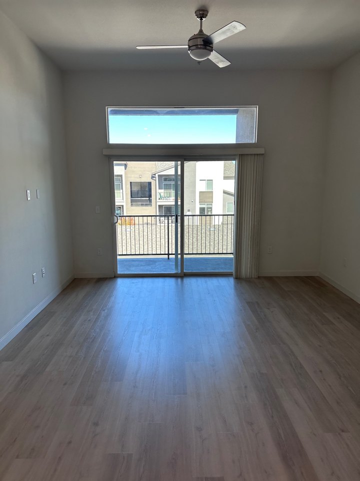 Living room with a sliding glass door, upper window, balcony access, and neighboring buildings visible in a Reno apartment